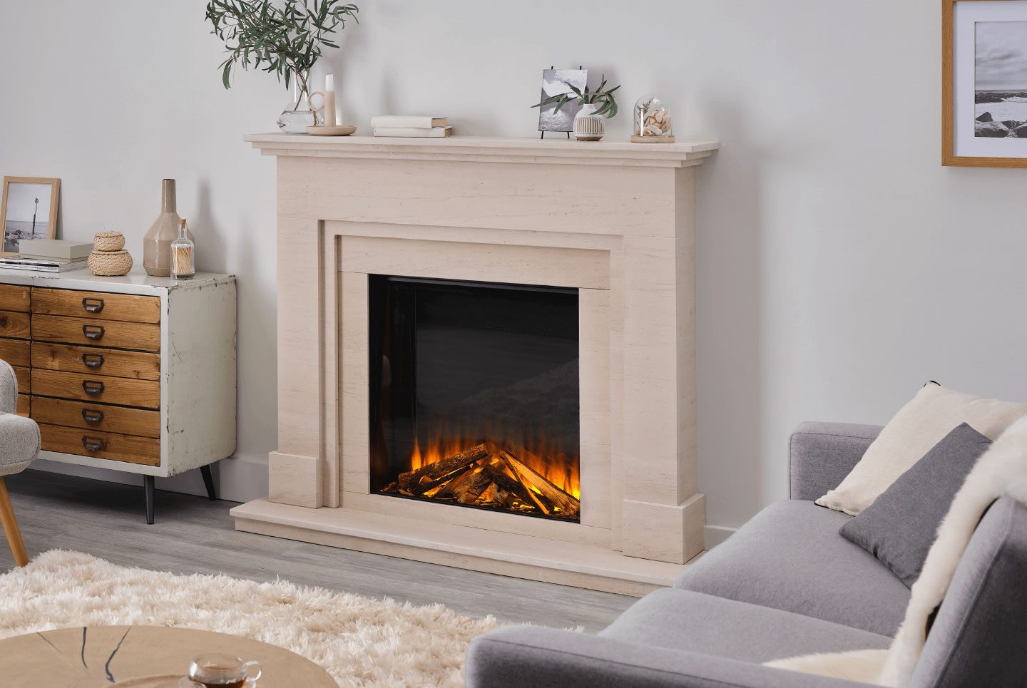 Modern living room featuring a stone fireplace with an electric flame effect and a grey sofa.